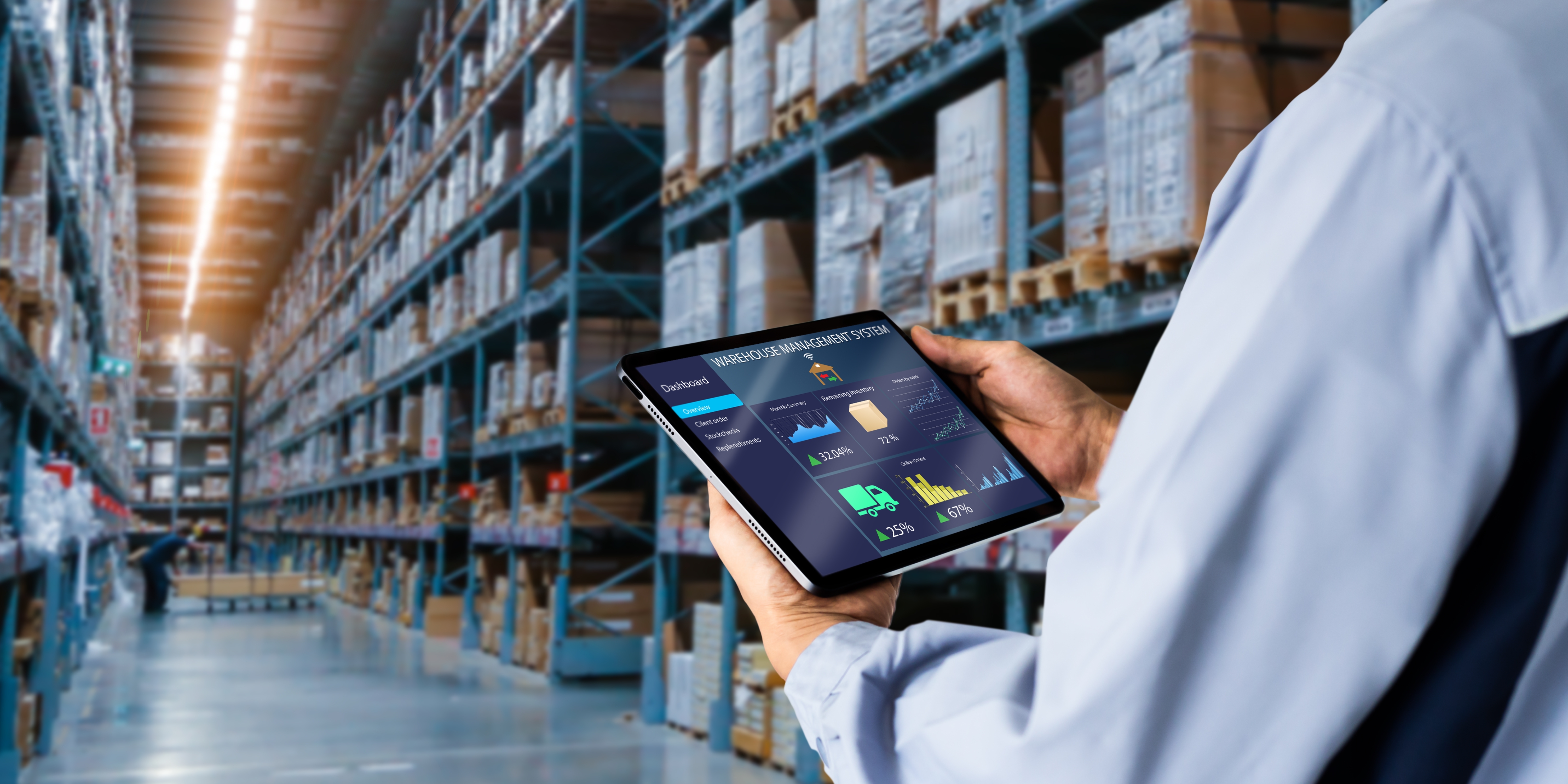 A person's arm holding a tablet in a warehouse